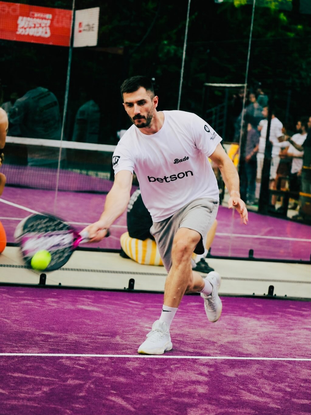 A player serving on a Bade padel court